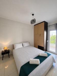 a white bedroom with a bed and a window at My Chios Apartments in Chios