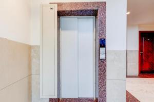 a glass elevator in a room with a red door at Super Townhouse Oak Sector 39 Medanta in Gurgaon