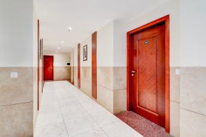 a hallway with a wooden door and a tile floor at Super Townhouse Oak Sector 39 Medanta in Gurgaon +46 photos