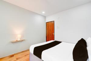 a white bedroom with a bed and a wooden door at Super Townhouse B N Reddy Formerly Capitol Stay Inn in Surūrnagar +24 photos