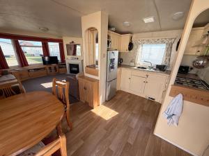 a kitchen and dining room with a table in a caravan at Bell Bank C8 - pet friendly, bed linen, close to bars and shops - Meadow Lakes Caravan & Lodge Hire in Chapel Saint Leonards
