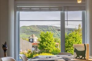 a dining room table with a view of a mountain through a window at EdenCat Condo - Mountain View in Beaupré