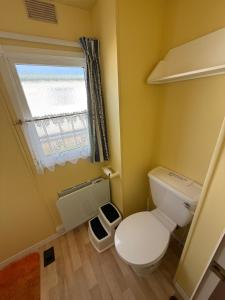 a small bathroom with a toilet and a window at Bell Bank C8 - pet friendly, bed linen, close to bars and shops - Meadow Lakes Caravan & Lodge Hire in Chapel Saint Leonards