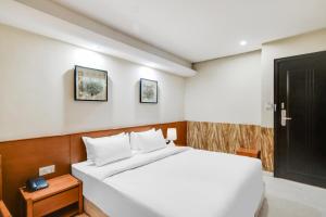 a bedroom with a white bed and a black door at Palette by CheckIn Chappan Market Indore Formerly Sapphire Star in Indore