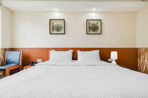 a bedroom with a large white bed and a blue chair at Palette by CheckIn Chappan Market Indore Formerly Sapphire Star in Indore