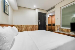 a bedroom with a large white bed and a television at Palette by CheckIn Chappan Market Indore Formerly Sapphire Star in Indore