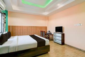 a bedroom with a bed and a desk and a television at Hotel O Eastern Crossway Siliguri Formerly Utsho in Siliguri