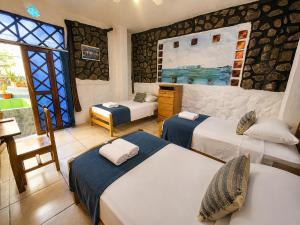a room with three beds and a couch and a window at Penguin Hostel in Puerto Ayora +58 photos