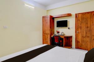 a bedroom with a bed and a desk with a television at Super Collection O Bashista Chariali Formerly Luit Heritage in Dispur +24 photos