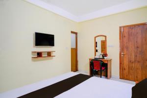 a bedroom with a bed and a tv on the wall at Super Collection O Bashista Chariali Formerly Luit Heritage in Dispur