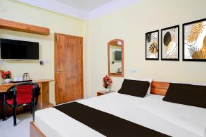 a bedroom with a bed and a desk and a television at Super Collection O Bashista Chariali Formerly Luit Heritage in Dispur