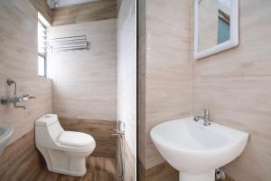 a bathroom with a white toilet and a sink at Super Collection O Bashista Chariali Formerly Luit Heritage in Dispur