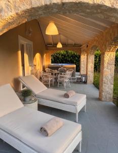 a patio with two beds and a table and chairs at Villa Armando Corfu Jacuzzi in Perama