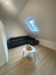 a living room with a black couch and a table at Le 3eme Mistral in Molsheim