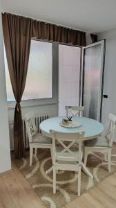 a white table and chairs in a room with windows at Apartman Pavlov 023 in Zrenjanin +38 photos