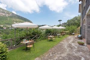 a patio with tables and umbrellas on the grass at Villevieille in Piano di Sorrento