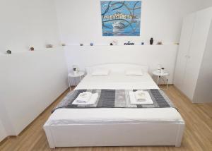a white bed in a white room with two tables at Apartment Murva in Primošten +20 photos