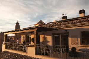 a building with a balcony with a clock tower in the background at La Casa dels Abeuradors in Gandesa