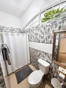 a bathroom with a toilet and a shower curtain at dela-de rose guesthouse in Negril