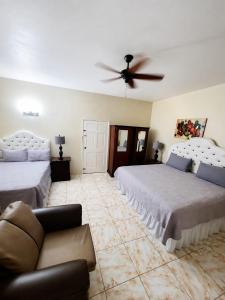 a bedroom with two beds and a ceiling fan at dela-de rose guesthouse in Negril