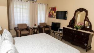 a bedroom with a bed and a mirror and a tv at dela-de rose guesthouse in Negril