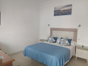 a bedroom with a bed with blue sheets and pillows at Hostal Arcos Beach Chipiona in Chipiona