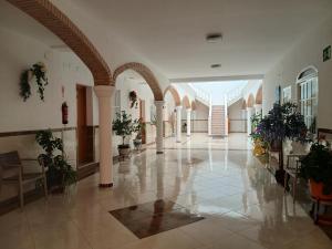 a hallway with pillars and potted plants in a building at Hostal Arcos Beach Chipiona in Chipiona