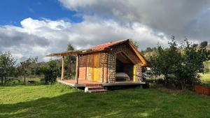 a small wooden hut in a grassy field at El Tiklan Glamping in Chucchilán