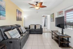 a living room with a couch and a flat screen tv at Villa Jardin - Infinity Pool and Backyard Oasis in Luquillo