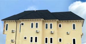 a large yellow building with a black roof at Sennet Luxury Hotel in Uyo
