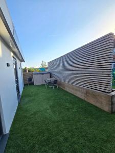 a backyard with a large retaining wall and grass at The Out House in Hemel Hempstead