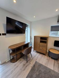 a room with a desk and a tv on a wall at The Out House in Hemel Hempstead