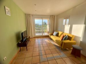a living room with a yellow couch and a television at Golf Paradise in Sant Jordi