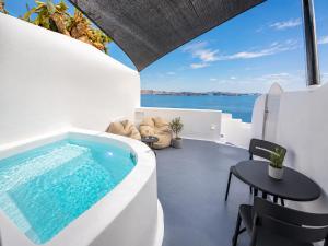 a pool in the middle of a room with a table and chairs at Three Domes Oia - an Iconic Collection in Oia