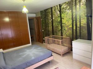 a bedroom with a crib and a forest mural at Apartamento en el Edificio Barlovento, situado en el centro de Alcossebre, a 150m del mar in Alcossebre