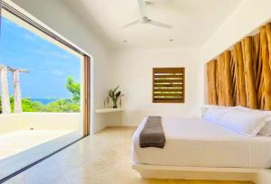 a bedroom with a bed and a large window at Casa Papelillo on Costa Careyes in Chamela +23 photos