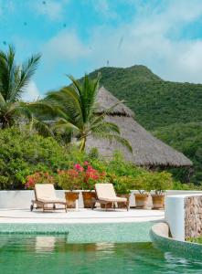 a resort pool with chairs and a thatch roof at Casa Papelillo on Costa Careyes in Chamela