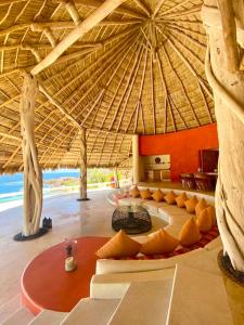 a living room with a couch under a straw roof at Casa Papelillo on Costa Careyes in Chamela