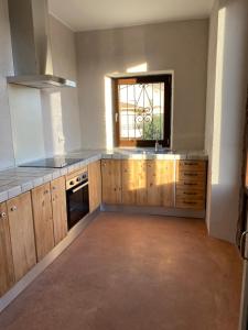 an empty kitchen with wooden cabinets and a window at Ca La Botera in Verges