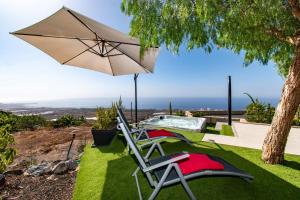 a pair of chairs and an umbrella next to a pool at Infinity House. Ocean View hot tub. in Adeje