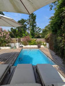 a swimming pool with chairs and an umbrella at Chambre confortable Piscine Maison EtxeCosy in Bidart