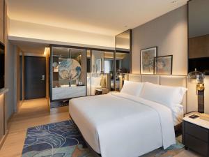 a bedroom with a large white bed and a large mirror at Mövenpick Hotel Jakarta City Centre in Jakarta