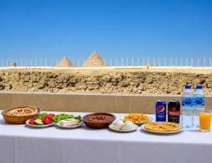 a table with plates of food and drinks on it at Shiny Pyramids Boutique Hotel in Cairo