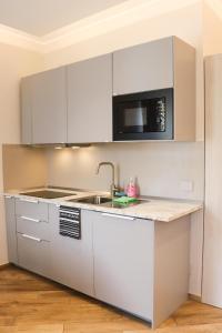 a white kitchen with a sink and a microwave at Sanremo Apartments - A Due Passi in Sanremo