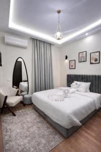 a bedroom with a large white bed and a chair at Villa Golden Sunset Pyramids in Cairo