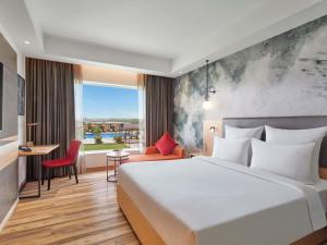a hotel room with a large bed and a window at Novotel Jaipur Convention Centre in Jaipur