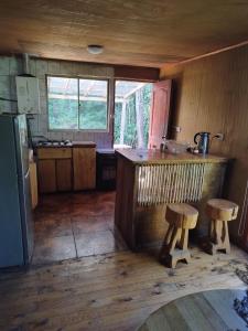 a kitchen with a counter and two wooden stools at Puñañas descanso y experiencias in Vilcún +3 photos