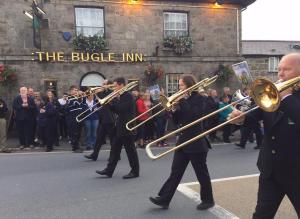 a group of people walking down a street with instruments at The Bugle Inn in Bugle