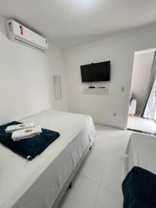 a white bedroom with a bed and a tv at Kitnet em Santo Antônio in Mata de Sao Joao