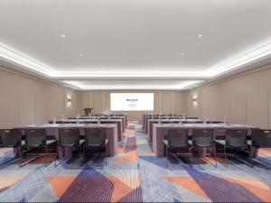 a conference room with tables and chairs and a projection screen at Mercure Xi'an Stadium Hotel in Xi'an